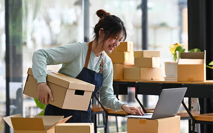 Frau Kennzeichnet Pakete und verpackt sie 