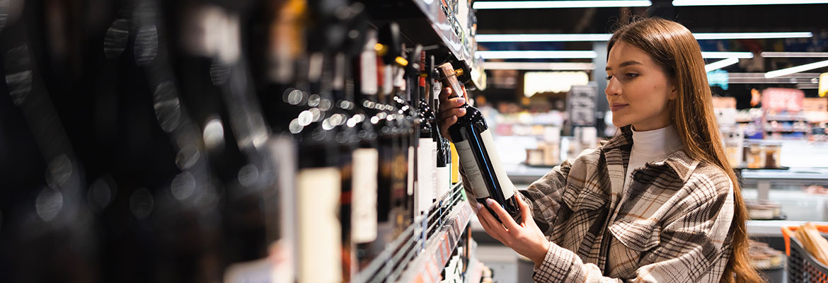 Wein kaufen im Supermarkt - Frau liest Etikett