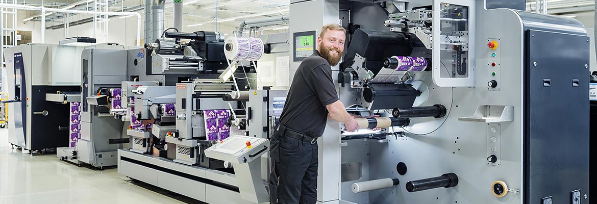 Produktionshalle von Labelprint24 - Mitarbeiter an Etikettenmaschine