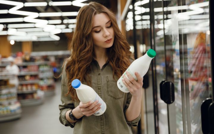 Frau liest Etikett einer Milchflasche 
