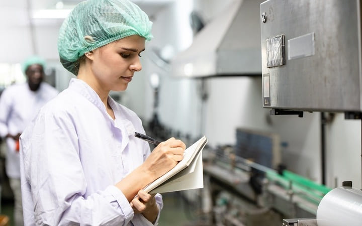 Mitarbeiterin kontrolliert Qualität in der Verpackungsherstellung für Lebensmittel nach HACCP Richtlinie